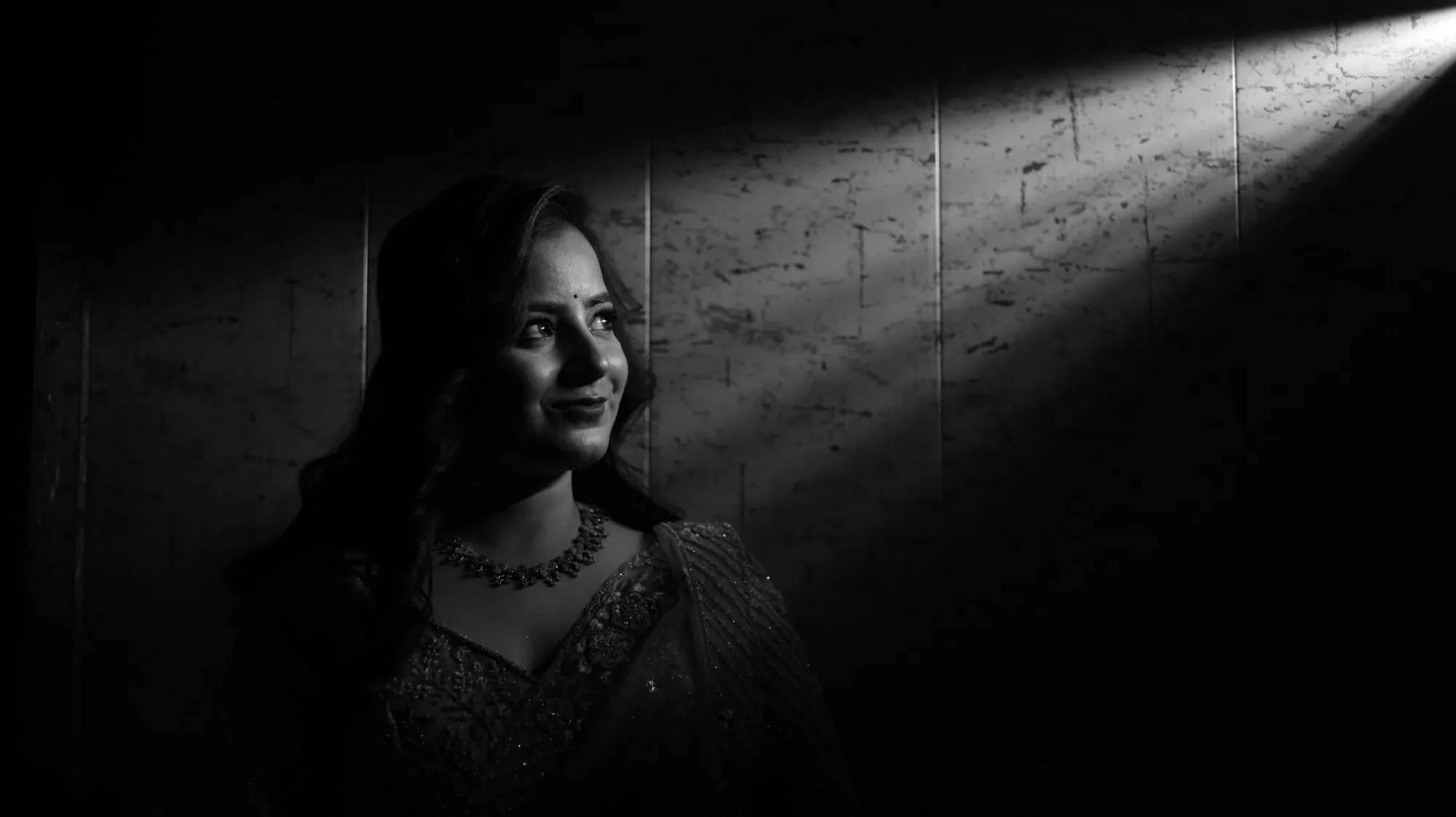 Black-and-white portrait in a saree lit by a beam of light