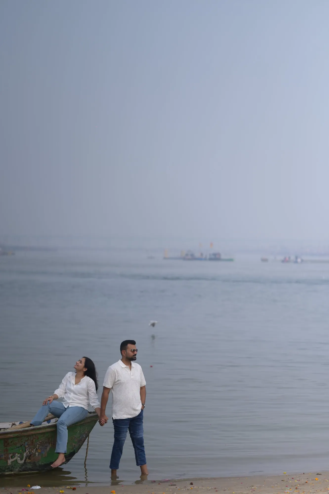 Couple on the Sangam shore beside a boat, Prayagraj